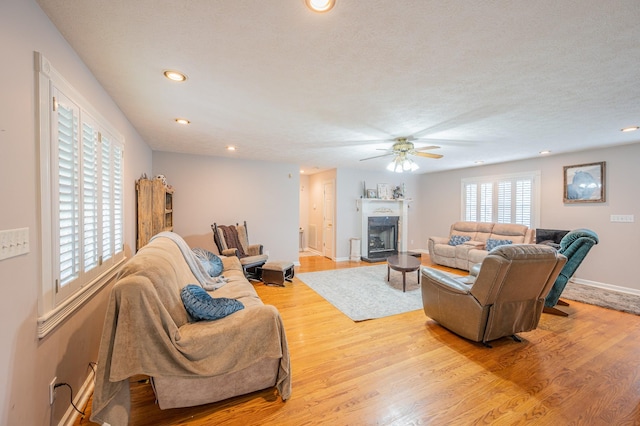 living room featuring ceiling fan, a textured ceiling, and light wood-type flooring