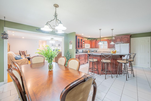 tiled dining area with ceiling fan with notable chandelier