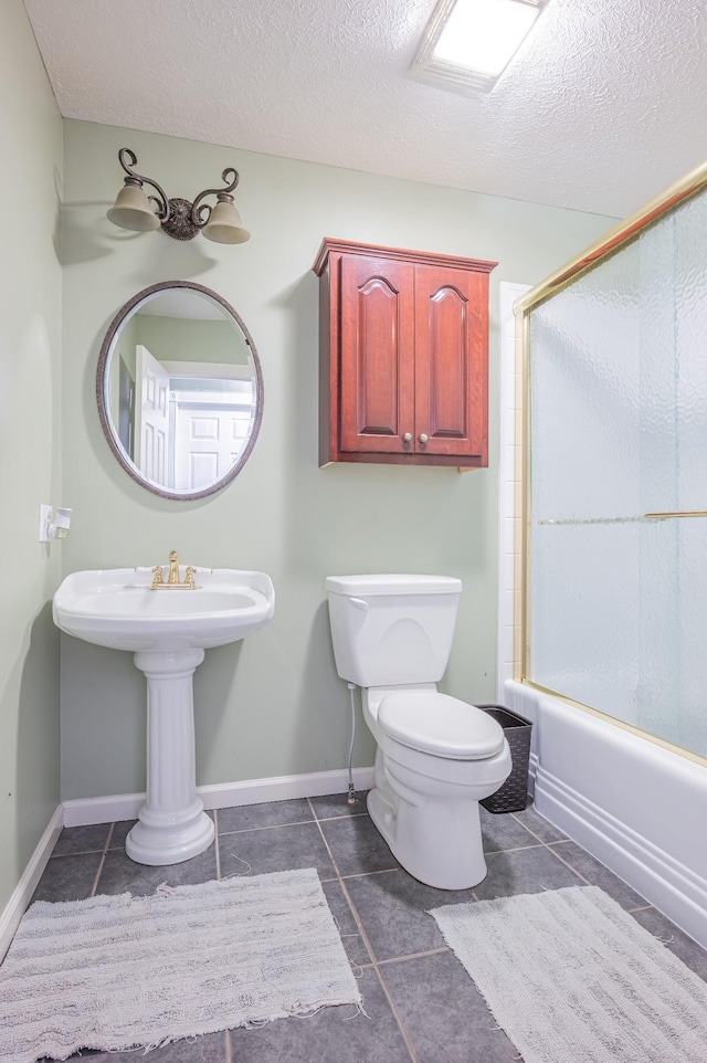 bathroom featuring shower / bath combination with glass door, tile patterned floors, a textured ceiling, and toilet