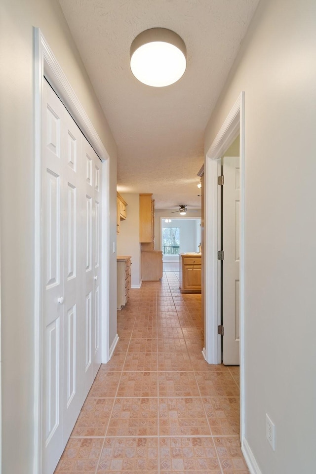 hallway with light tile patterned flooring and a textured ceiling