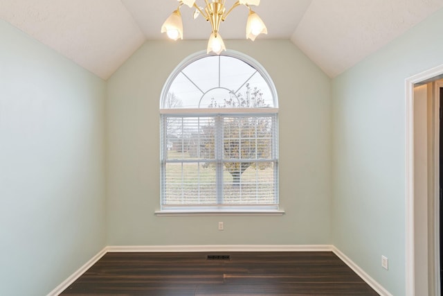 empty room featuring plenty of natural light, lofted ceiling, and dark wood-type flooring