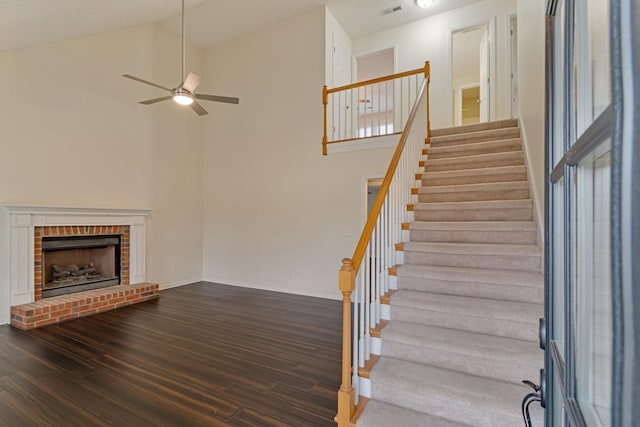 unfurnished living room with ceiling fan, a fireplace, high vaulted ceiling, and dark wood-type flooring