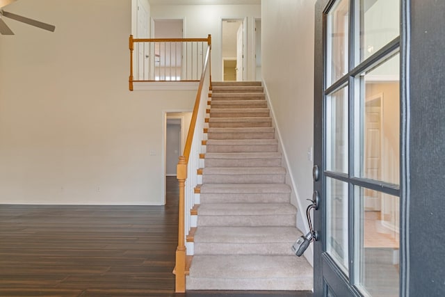 staircase with ceiling fan, wood-type flooring, and a high ceiling