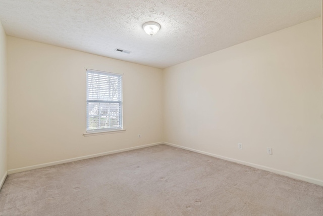 unfurnished room with light colored carpet and a textured ceiling