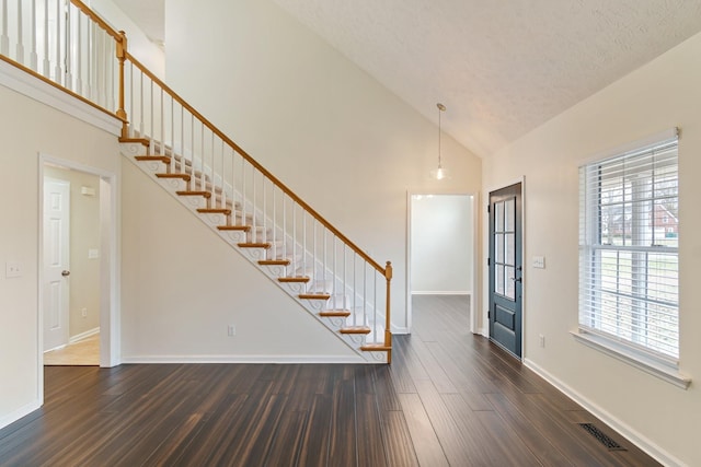 entrance foyer with a textured ceiling, dark hardwood / wood-style flooring, and high vaulted ceiling