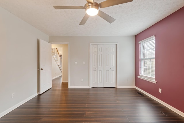 unfurnished bedroom with ceiling fan, dark hardwood / wood-style flooring, a textured ceiling, and a closet