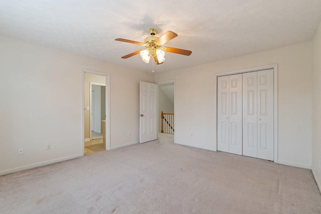 unfurnished bedroom featuring ceiling fan, a closet, light carpet, and a textured ceiling