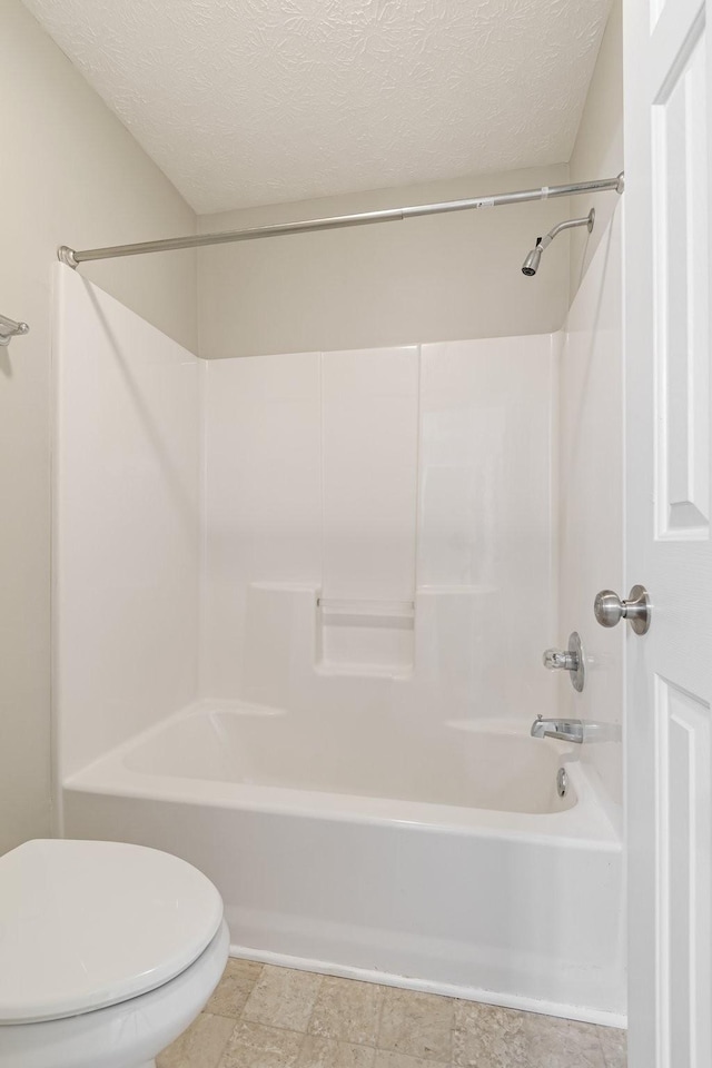 bathroom with toilet, shower / tub combination, and a textured ceiling