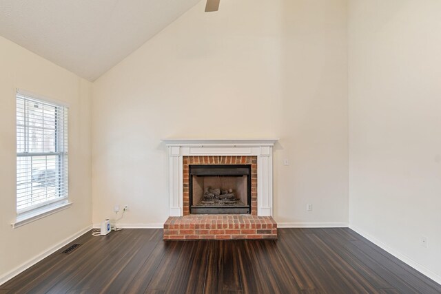 unfurnished living room featuring high vaulted ceiling, dark wood-type flooring, and a brick fireplace