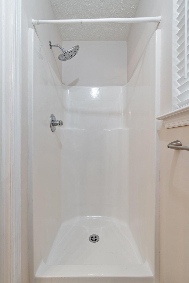 bathroom with a textured ceiling and walk in shower