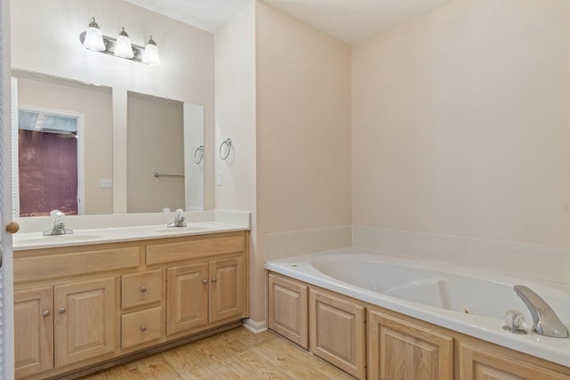 bathroom featuring vanity, a tub to relax in, a textured ceiling, and hardwood / wood-style flooring