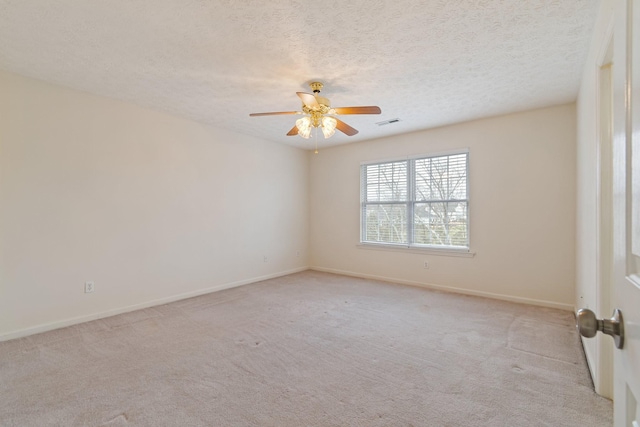 spare room featuring ceiling fan, light colored carpet, and a textured ceiling