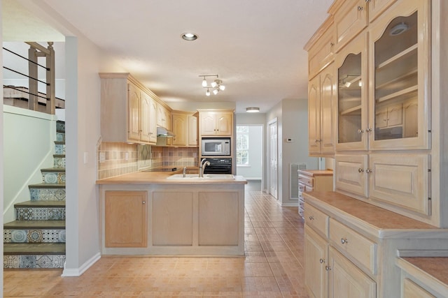 kitchen with kitchen peninsula, backsplash, sink, black appliances, and light brown cabinets