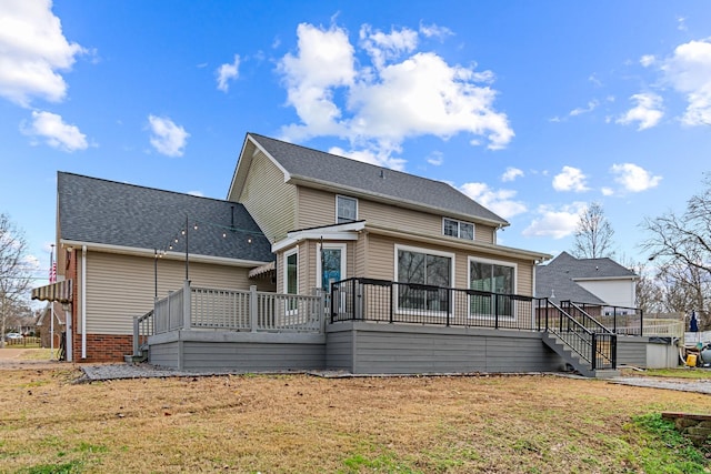 back of property featuring a deck and a lawn