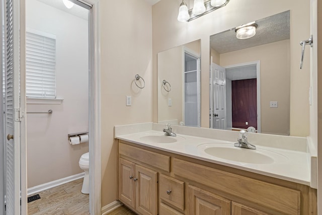 bathroom with toilet, vanity, a textured ceiling, and hardwood / wood-style flooring