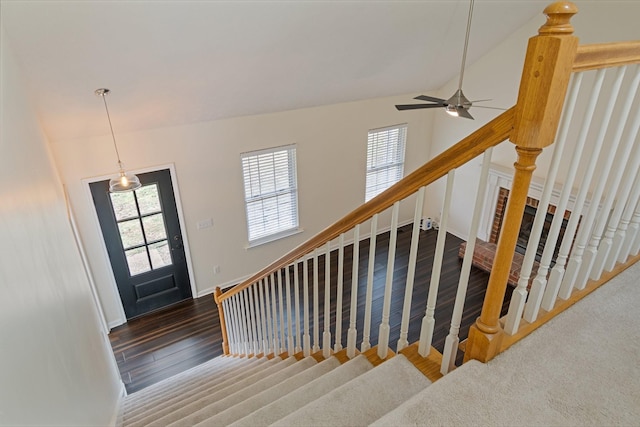 staircase featuring plenty of natural light, ceiling fan, wood-type flooring, and vaulted ceiling