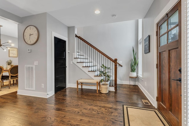 foyer with dark hardwood / wood-style floors and an inviting chandelier