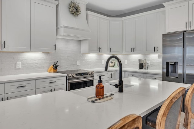 kitchen featuring premium range hood, white cabinetry, and appliances with stainless steel finishes