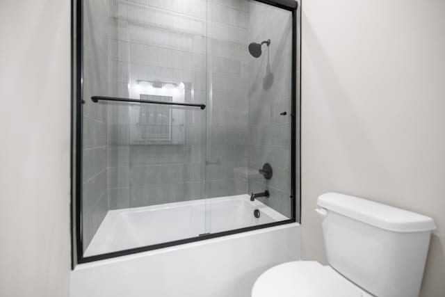 bathroom with combined bath / shower with glass door and toilet