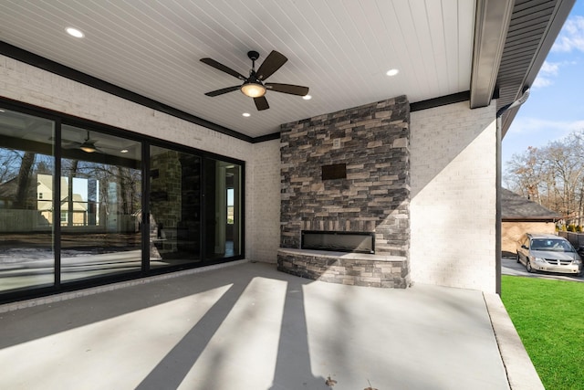 view of patio / terrace featuring ceiling fan and an outdoor stone fireplace