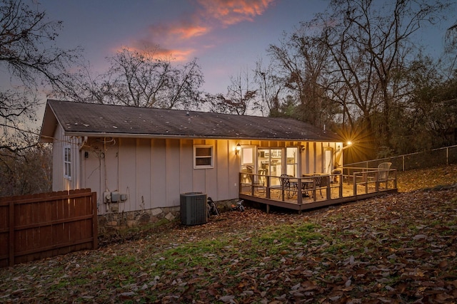 back house at dusk featuring a deck and cooling unit