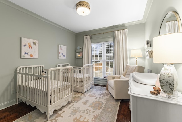 bedroom featuring wood-type flooring, a crib, and ornamental molding