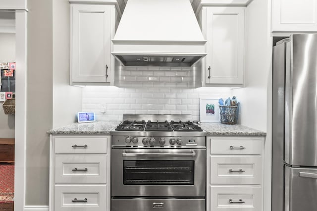 kitchen featuring tasteful backsplash, white cabinets, stainless steel appliances, and custom range hood