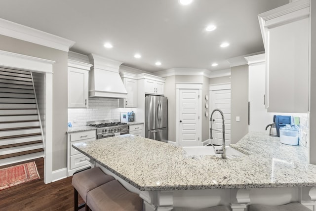 kitchen featuring premium range hood, stainless steel appliances, a breakfast bar area, and dark wood-type flooring