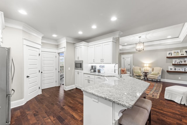 kitchen with a breakfast bar, dark wood-type flooring, kitchen peninsula, appliances with stainless steel finishes, and white cabinetry