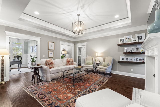 living room featuring hardwood / wood-style floors, a tray ceiling, an inviting chandelier, and ornamental molding