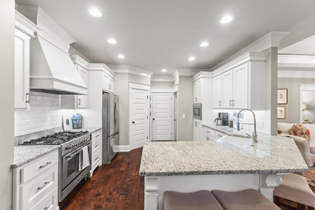 kitchen with light stone countertops, sink, stainless steel appliances, a kitchen breakfast bar, and dark hardwood / wood-style flooring