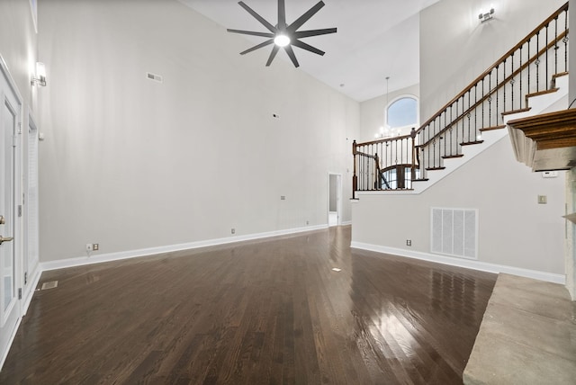 unfurnished living room featuring ceiling fan with notable chandelier, high vaulted ceiling, and dark hardwood / wood-style floors