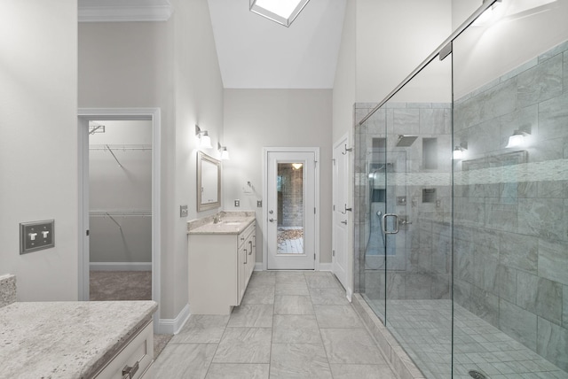 bathroom featuring a shower with door, vanity, a high ceiling, and ornamental molding