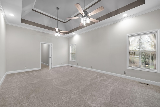 carpeted empty room with a raised ceiling, ceiling fan, and crown molding