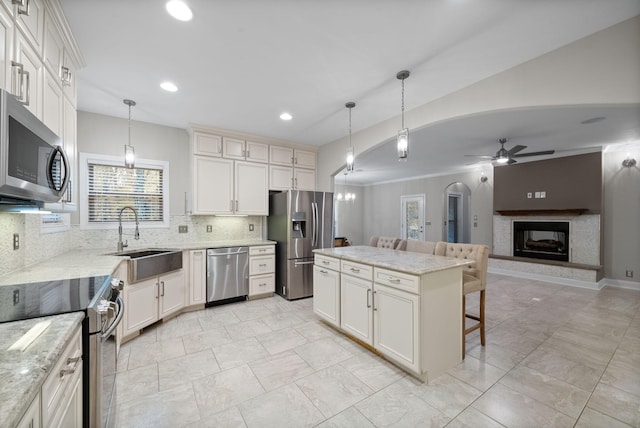 kitchen featuring a center island, sink, hanging light fixtures, decorative backsplash, and appliances with stainless steel finishes