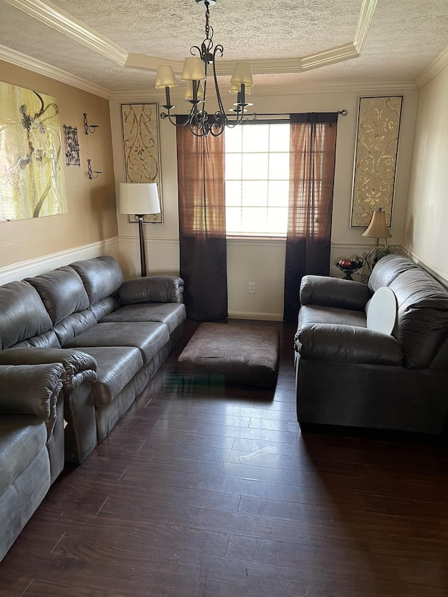 living room featuring a tray ceiling, crown molding, dark hardwood / wood-style flooring, and an inviting chandelier