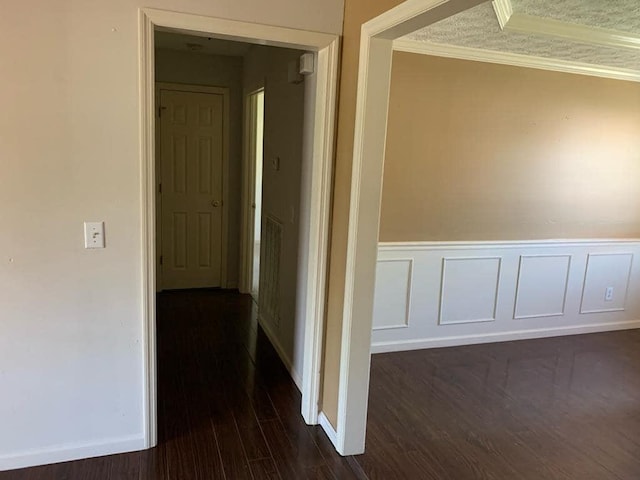 hallway with dark hardwood / wood-style floors and crown molding