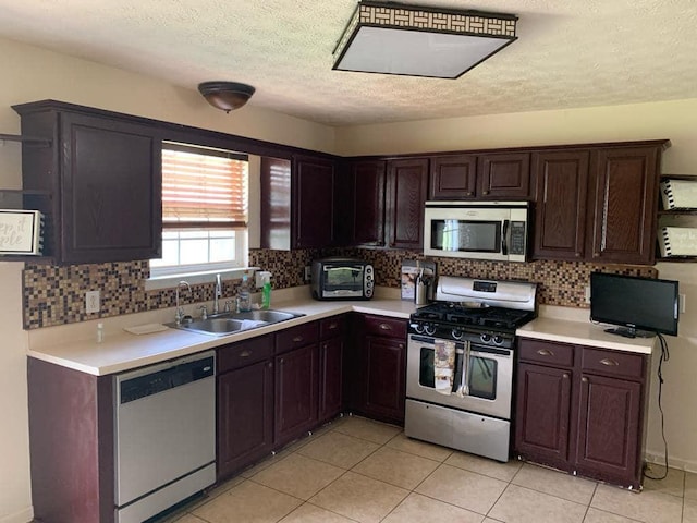 kitchen featuring dark brown cabinetry, stainless steel appliances, a textured ceiling, sink, and light tile patterned floors