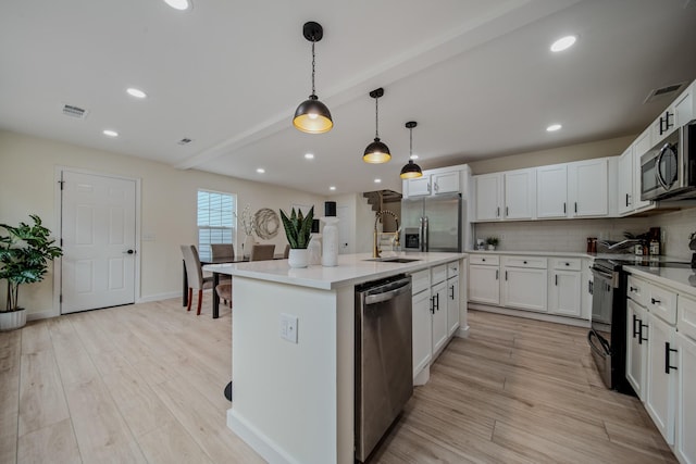 kitchen with white cabinetry, hanging light fixtures, an island with sink, and stainless steel appliances