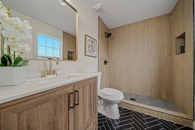 bathroom with vanity, toilet, and tiled shower