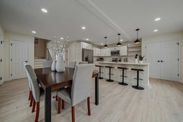 dining space with beam ceiling and light hardwood / wood-style flooring