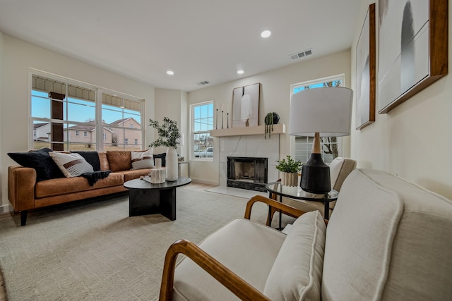 living room with a tile fireplace and light carpet