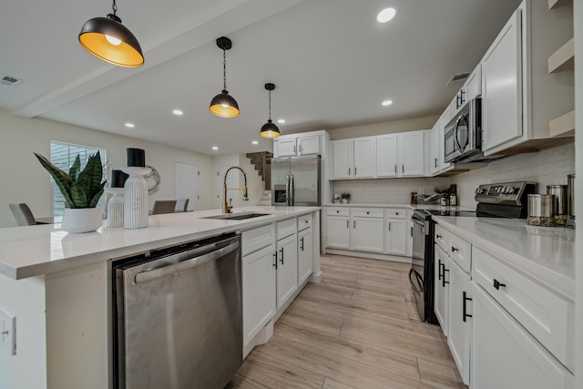 kitchen featuring decorative light fixtures, white cabinetry, sink, and appliances with stainless steel finishes