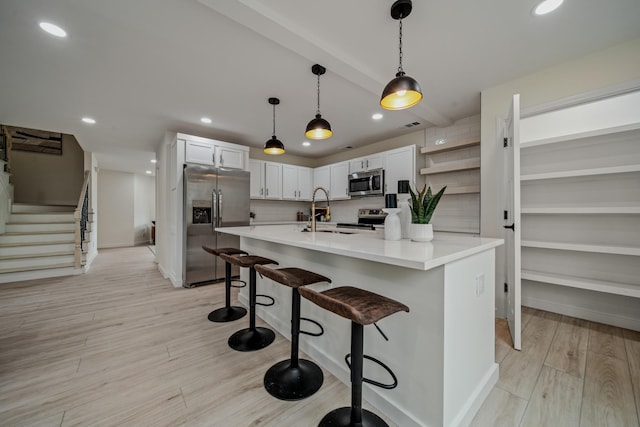 kitchen featuring white cabinetry, sink, stainless steel appliances, light hardwood / wood-style floors, and a breakfast bar area