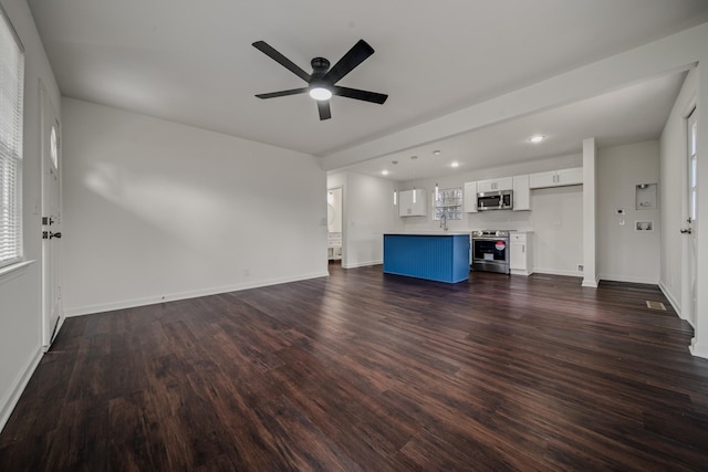 unfurnished living room with a wealth of natural light, ceiling fan, and dark hardwood / wood-style floors