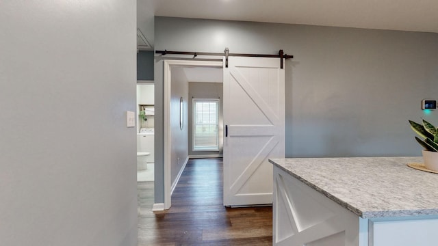 interior space with a barn door, washer / clothes dryer, and dark hardwood / wood-style floors