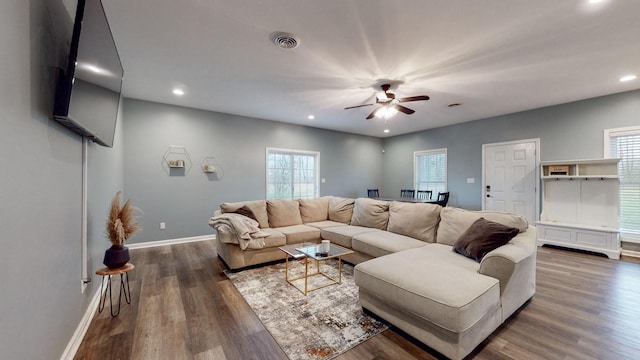 living room with a wealth of natural light, ceiling fan, and dark wood-type flooring