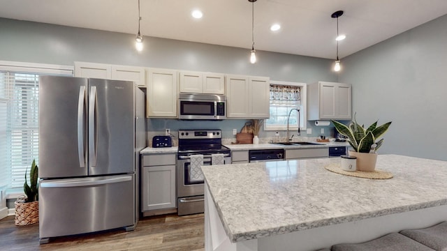 kitchen with dark wood-type flooring, white cabinets, sink, appliances with stainless steel finishes, and decorative light fixtures