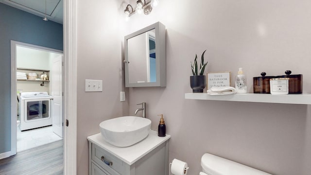 bathroom featuring toilet, hardwood / wood-style floors, vanity, and washer / dryer