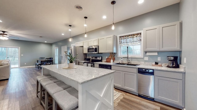 kitchen featuring appliances with stainless steel finishes, ceiling fan, sink, pendant lighting, and light hardwood / wood-style floors